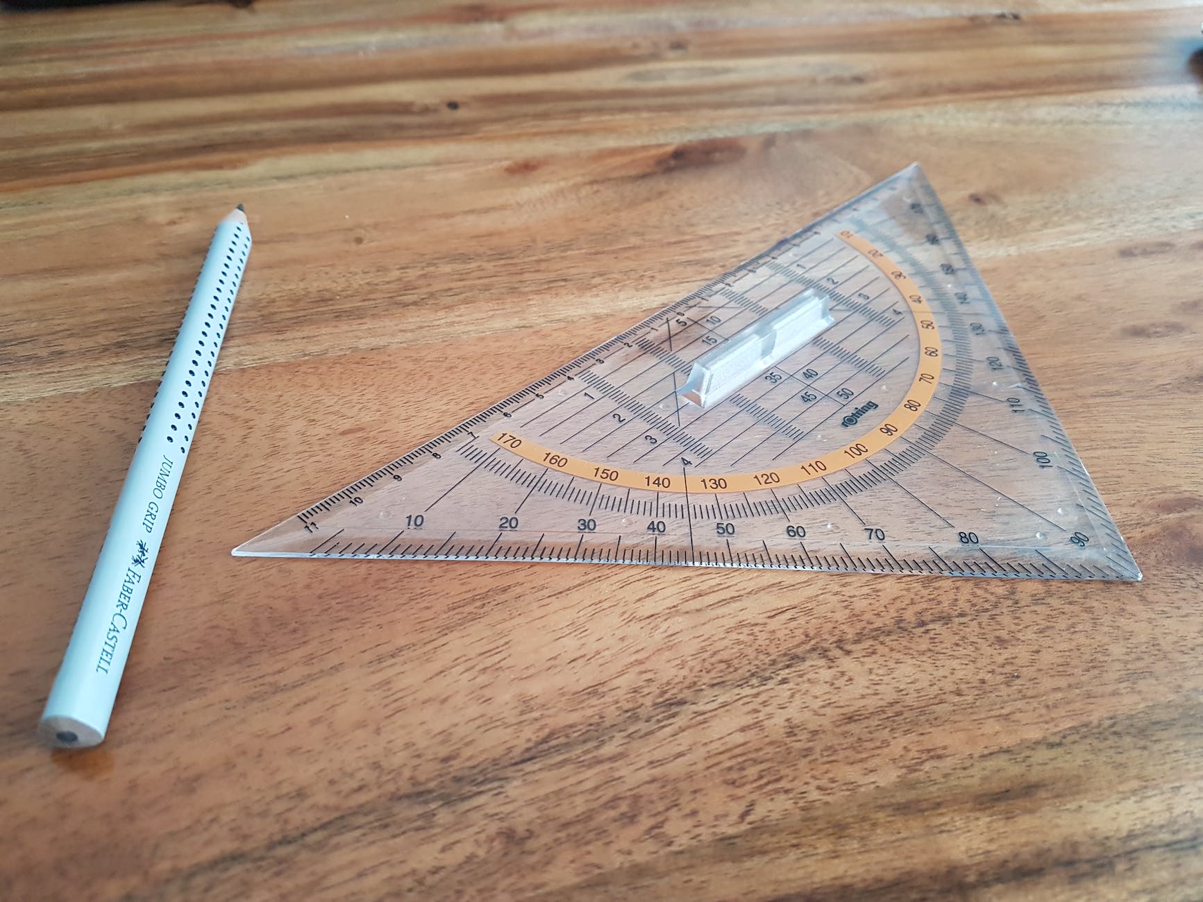 gray pencil and triangular ruler on brown wooden surface